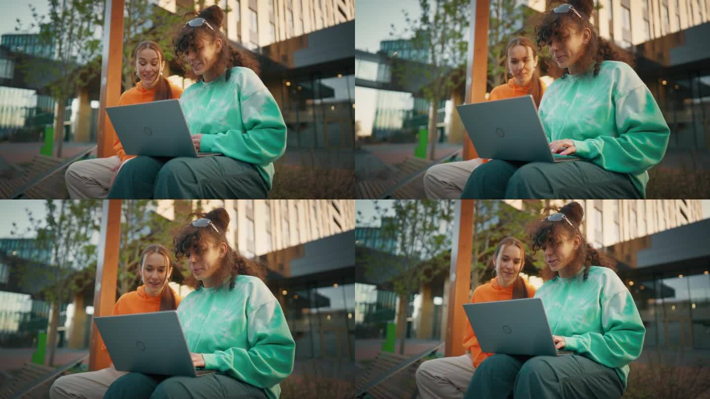 两位大一女生正在校外用笔记本电脑一起做作业。年轻女性追求高等教育，讨论思想，备课。