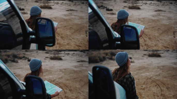在沙漠的某个地方，一名妇女看着她的露营车前的地图