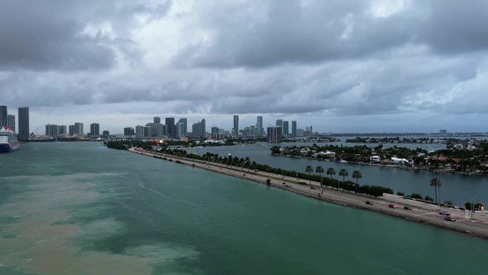在一个温暖的阴天，佛罗里达州迈阿密的热门邮轮港口，一条繁忙的高速公路被水包围，水中的污垢来自船只的移