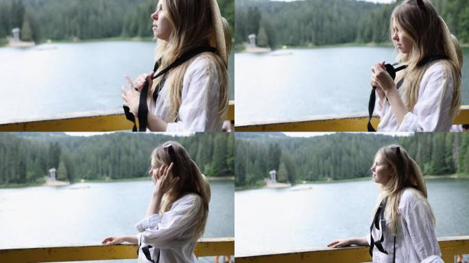 美丽的金发女孩戴着草帽，系着黑丝带，背景是山中的一个湖。一个女人看着Synevir湖。中期计划