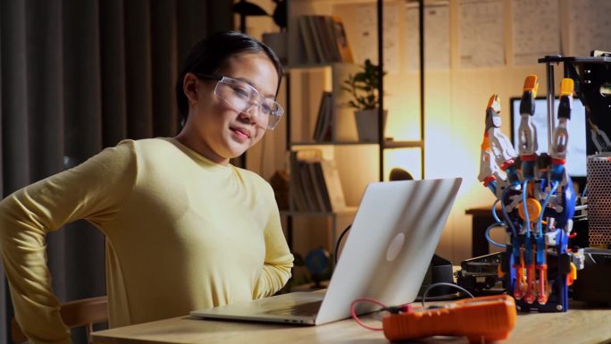 十几岁的亚洲女孩在家里用笔记本电脑摆弄电子手时腰疼