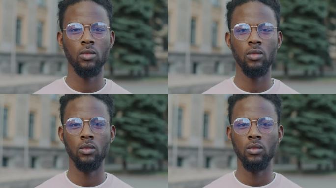 非裔美国学生戴眼镜站在户外，表情严肃的慢动作肖像