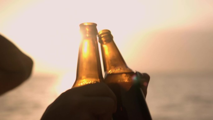 夏日里，一对年轻夫妇站在沙滩上喝啤酒