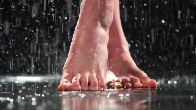 没穿鞋的女人在雨中跷二郎腿踮着脚尖站着