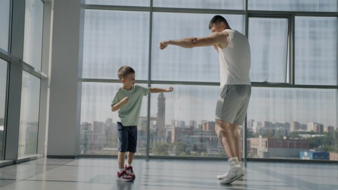 父子俩在体育馆里一起练习拳击动作的慢动作