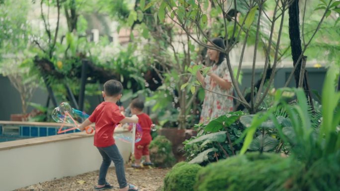 无忧无虑的夏日乐趣:亚洲男孩和他的妈妈在公园吹泡泡-户外快乐和亲密