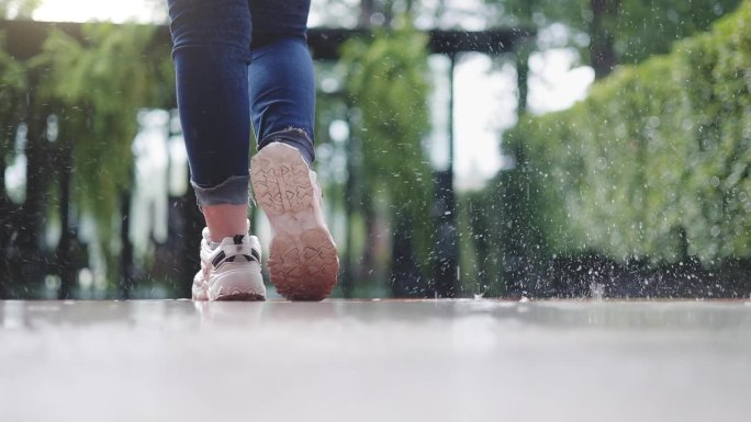 美丽的少女站在雨中的脚的特写镜头