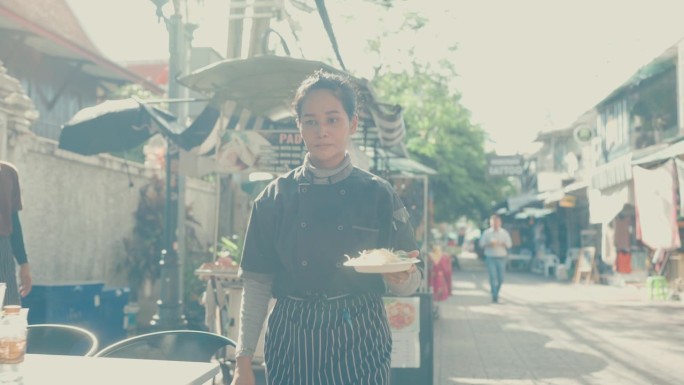 泰国饮食文化:女厨师在市场准备传统泰式炒粉。