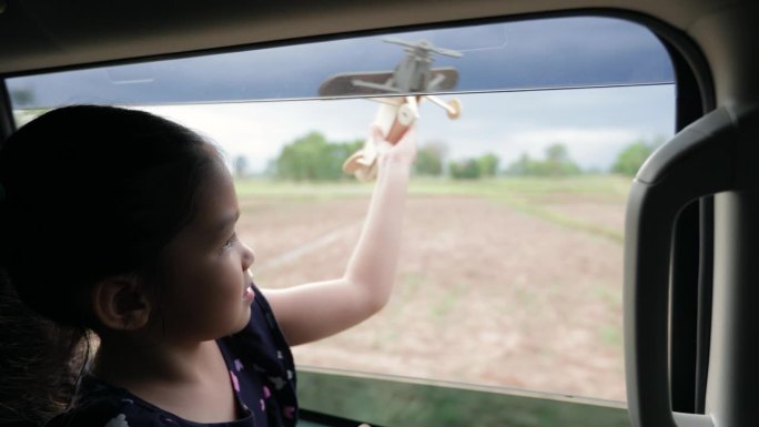 小女孩正在窗外玩玩具木飞机