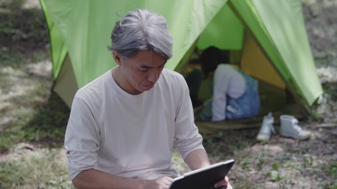 一位日本企业家在露营时查看工作邮件。