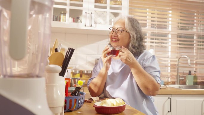 4K亚洲老妇人在厨房使用带有社交媒体的智能手机。