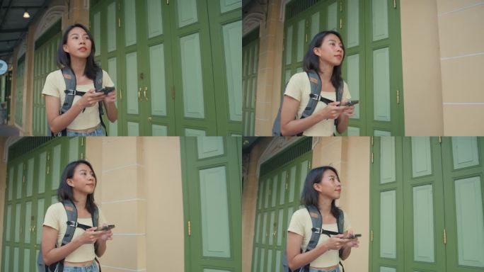 年轻的亚洲女背包客在城市街道上使用手机。假日度假旅行概念。
