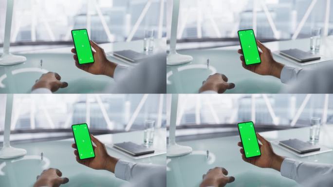 商人手持智能手机模拟绿屏Chromakey显示与运动跟踪占位符。一个不知名的男人坐在现代办公室的桌子