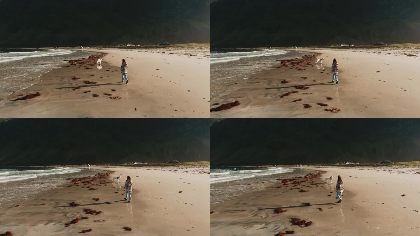 小女孩和白狗在厄斯峡湾海滩散步。女孩直视镜头。
