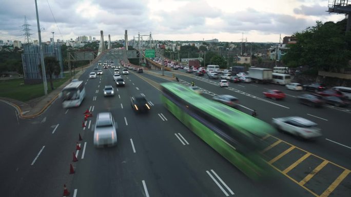 广角延时拍摄的许多汽车和卡车行驶在高速多车道公路胡安博世大桥在圣多明各的夜晚。模糊运动城市交通堵塞的