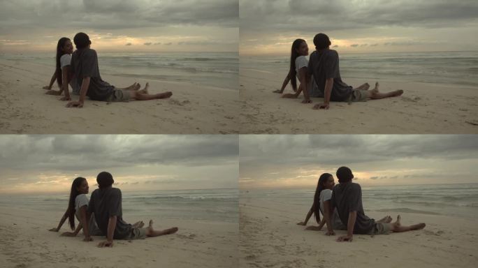 年轻夫妇坐在海边聊天，望着别处