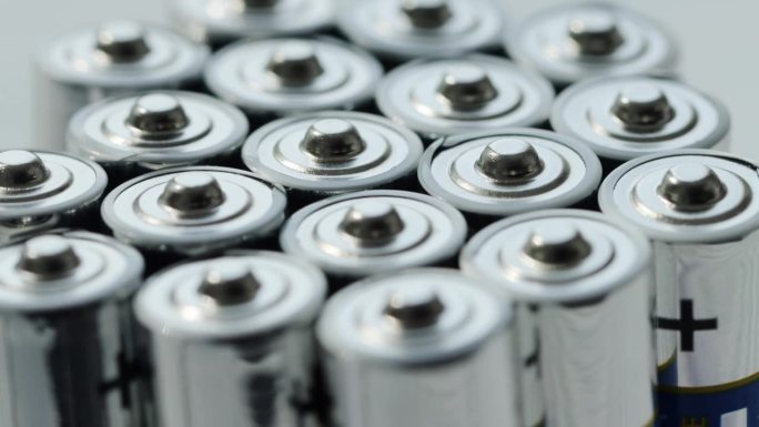 大量的碱性充电电池具有不同的极性和功率。电池回收，正负，背景。绕自己的轴旋转。宏