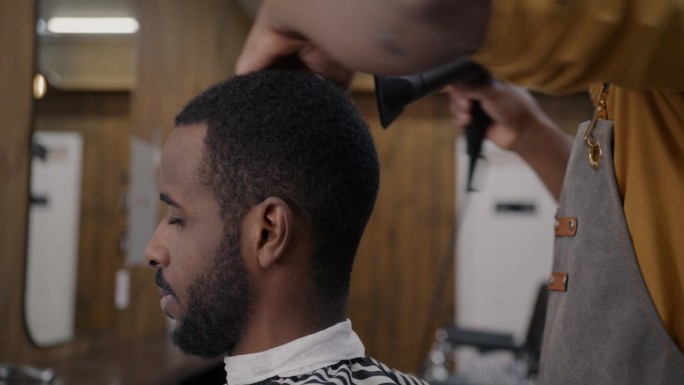非裔美国人在理发店用现代吹风机吹干头发的特写