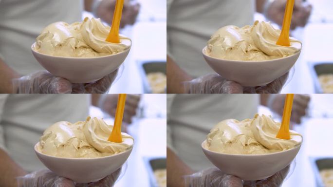 一碗咸焦糖味冰淇淋，黄色勺子伸出来，特写