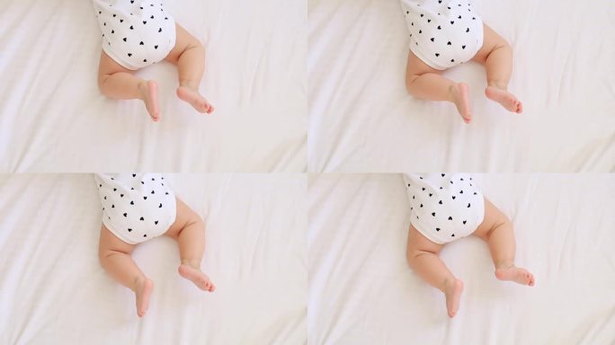 一个小孩的腿躺在浅色的床上或白色的背景上，一个书写文字的地方，一个婴儿的脚
