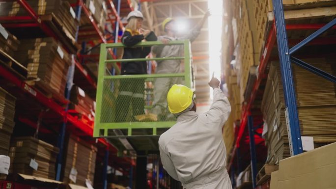 两个仓库工人在叉车上检查制造工厂的货架上的库存纸板造纸厂。