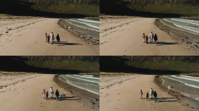 一架无人机在挪威厄斯峡湾海滩拍摄了一个带着两个孩子和一只狗在海边散步的年轻家庭