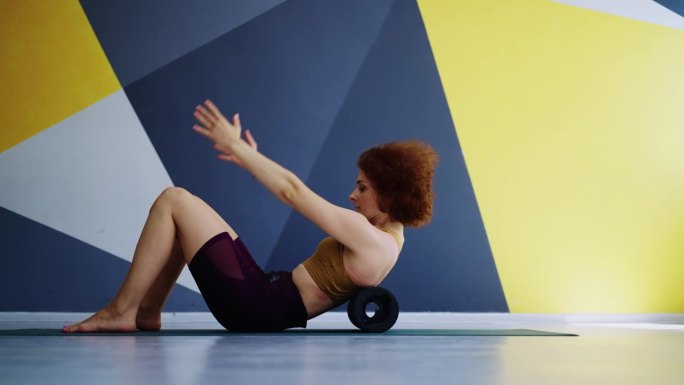 在健身房用滚轮运动健身，苗条的运动女性在健身俱乐部独自训练