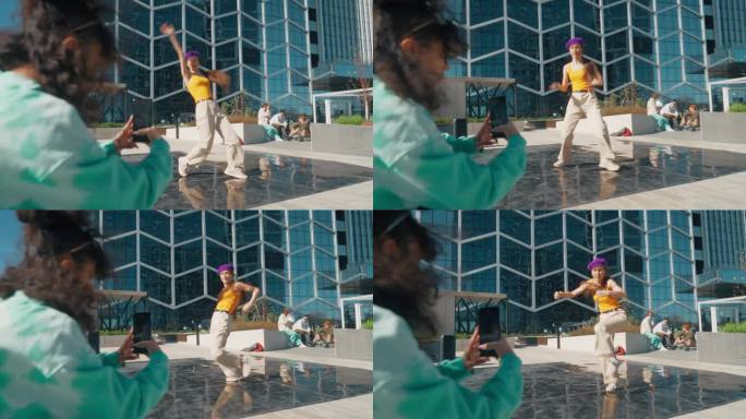 年轻时尚的女嘻哈舞者在城市街道上自由表演。朋友在社交媒体上用智能手机录下了她的视频。年轻女子在现代市