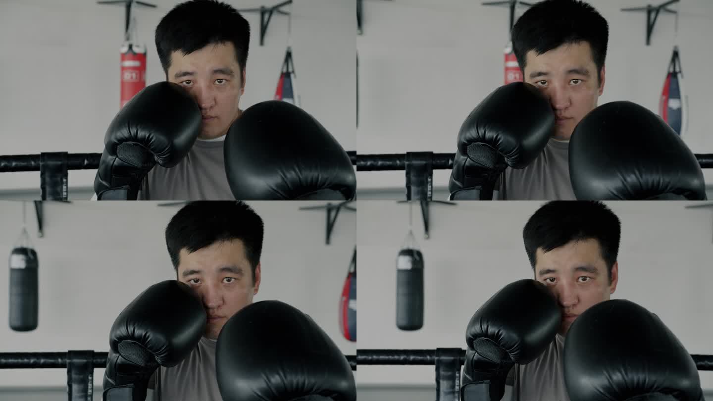 慢动作的年轻亚洲男子拳击手站在角落里戴着手套准备战斗看着镜头