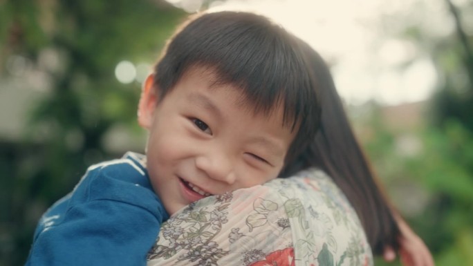 在家的幸福:慈爱的亚洲妈妈把兴奋的儿子扔到前院的空中。