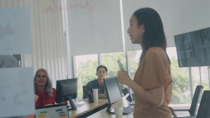 亚洲女性，在办公室的玻璃板上书写和解释业务策略。