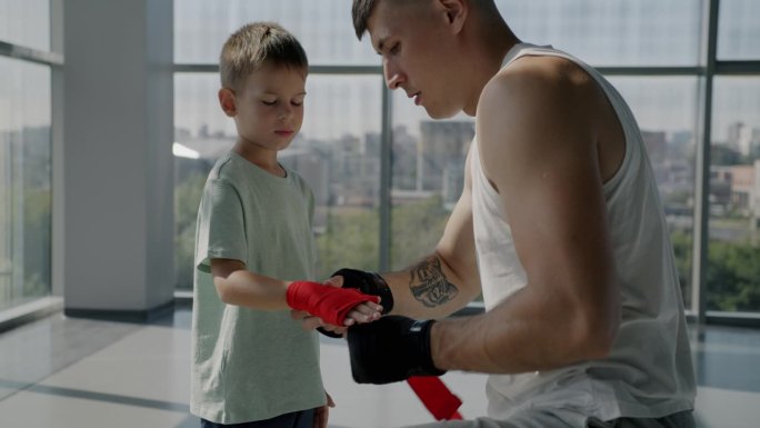 拳击手父亲和小儿子在室内体育馆准备进行拳手保护训练