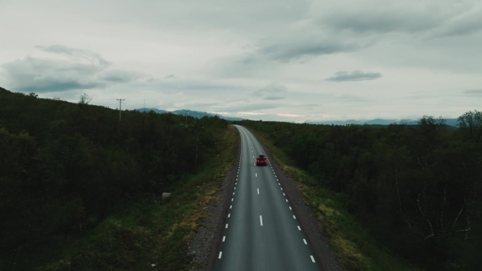 红色越野车独自行驶在空旷的车道上，绿色的北欧风景