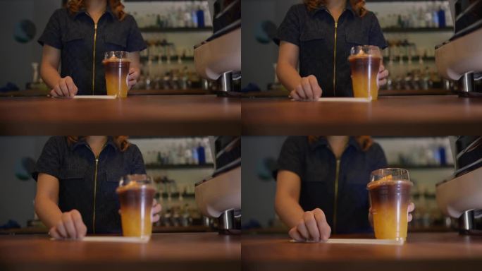 年轻的女咖啡师正在为顾客端上一杯橙汁咖啡。