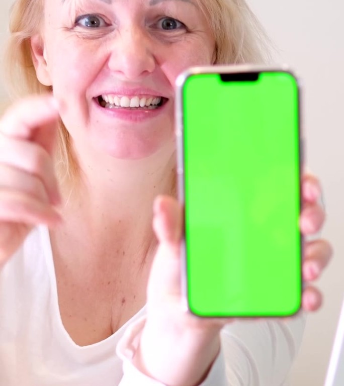 女人似乎正在输入信息或打开某个网站，然后把屏幕变成绿色，而不是广告，大拇指竖起，微笑着，笑着，用手指