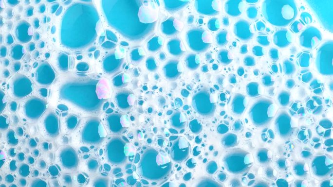 肥皂泡沫在蓝色的水面上冒泡。肥皂泡沫。背景灰尘泡沫与泡沫。运动中的肥皂