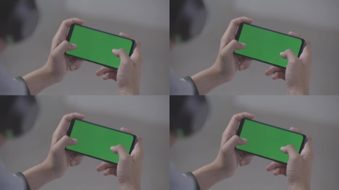 亚洲男子戴耳机玩绿屏智能手机