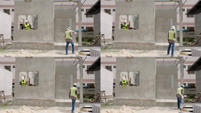 亚洲建筑师和工程师正在检查在建房屋的结构。工作时佩戴绿色反光背心和安全帽，确保安全。多民族人民的合作
