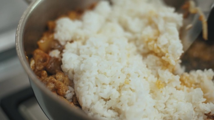 在锅里加入米饭，用平底锅煎猪肉和泡菜，翻炒。