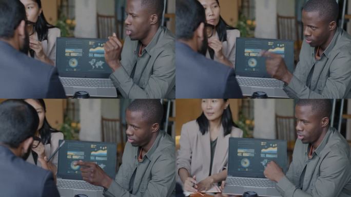 非洲裔美国商人指着笔记本电脑屏幕和咖啡馆里的合伙人交谈