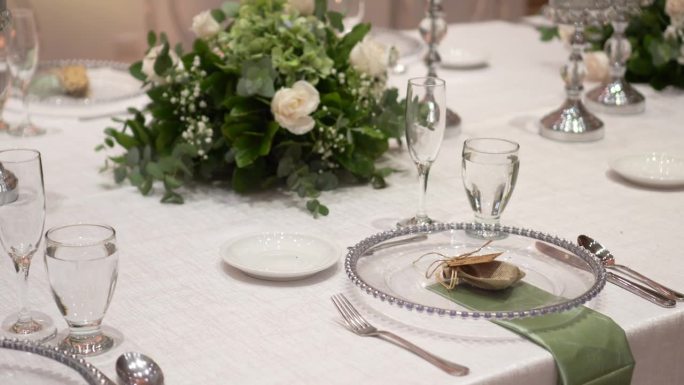 用鲜花装饰的婚礼餐桌布景。婚礼花艺。宴会桌供客人使用。玫瑰、尤加利树叶的香味
