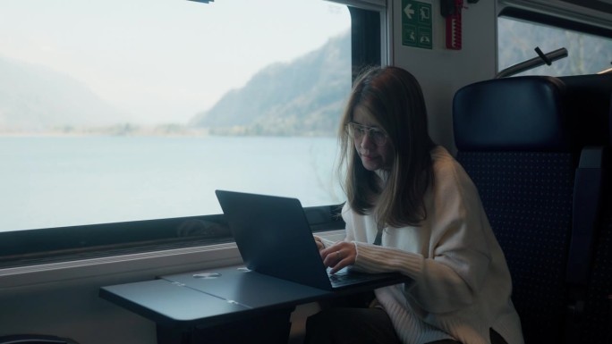 出差期间在高铁上用笔记本电脑工作的亚洲女性。