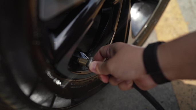 男机械师正在给汽车轮胎充气，给他的汽车轮胎充气控制器的轮胎充气。