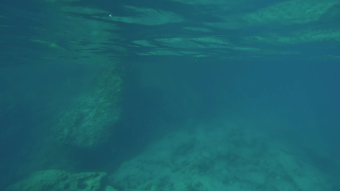 POV水下镜头，镜头向前移动到岩石海岸，在水下下降，浮出水面