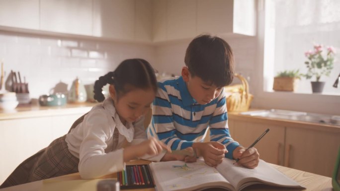 韩国家庭在厨房里的照片:可爱的孩子们在妈妈准备午餐的时候陪伴着她。他们在画画和上色，而他们的妈妈正在