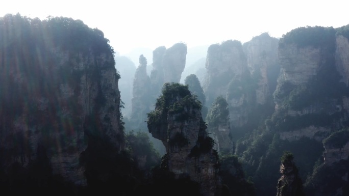中国湖南武陵源张家界，蓝色阴霾的太阳耀斑穿过岩石尖塔