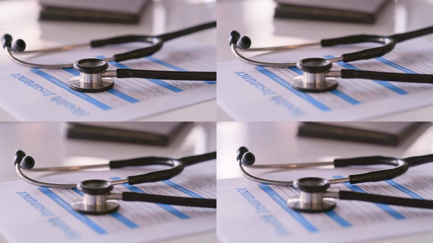 医院办公桌上的特写，听诊器和人寿保险文件，申请或医疗文书。带有健康表格、调查或临床结果文书的医疗设备