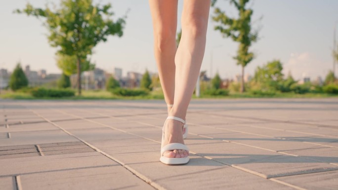 穿着高跟凉鞋的美女腿优雅地漫步在阳光城市公园