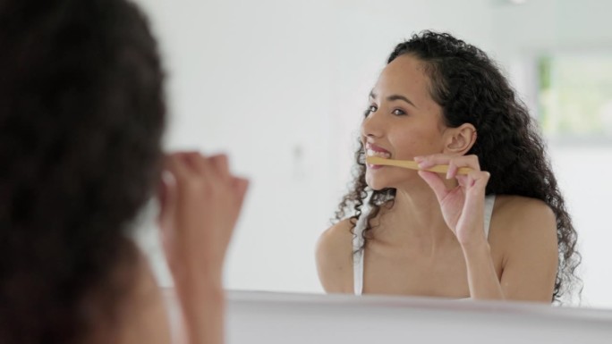 妇女在家时，用牙刷和对着镜子刷牙，以保持口腔卫生或清洁浴室。快乐的女性在早上例行清洁牙齿，口腔或口腔