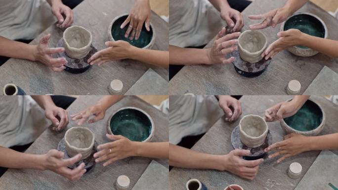 在陶轮上做陶罐的男女手